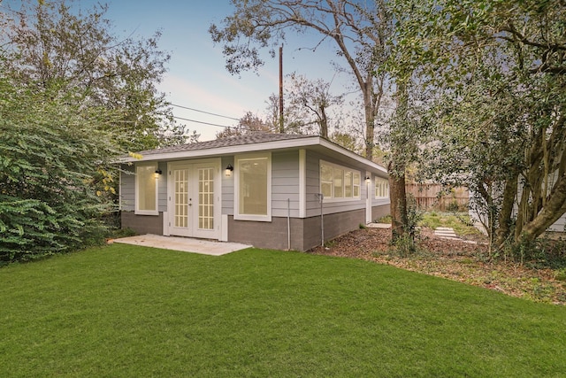 back house at dusk with a lawn and french doors