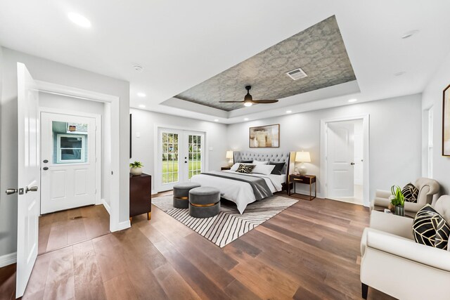 bedroom with hardwood / wood-style floors, french doors, access to exterior, a raised ceiling, and ceiling fan