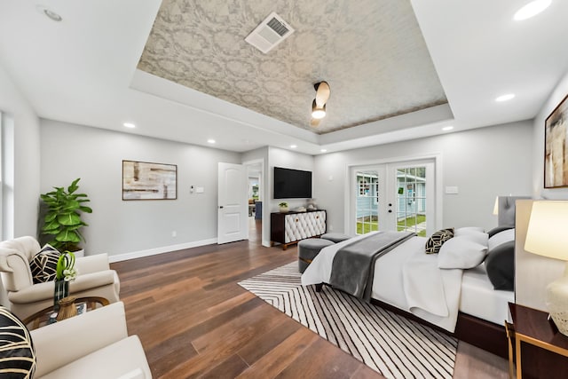 bedroom with dark wood-type flooring, access to exterior, a tray ceiling, and french doors