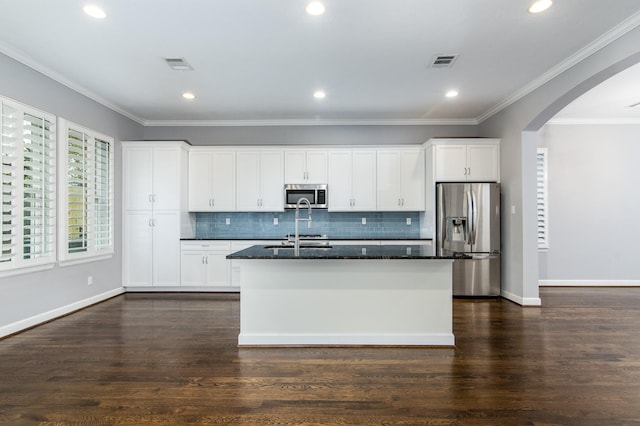 kitchen featuring white cabinetry, an island with sink, appliances with stainless steel finishes, dark wood-type flooring, and dark stone counters