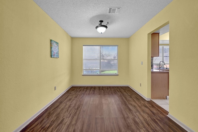 unfurnished room featuring a textured ceiling, wood-type flooring, and sink