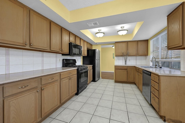 kitchen featuring black appliances, sink, a tray ceiling, and tasteful backsplash