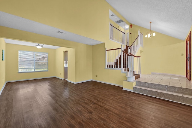 unfurnished living room with a textured ceiling, an inviting chandelier, lofted ceiling, and hardwood / wood-style flooring