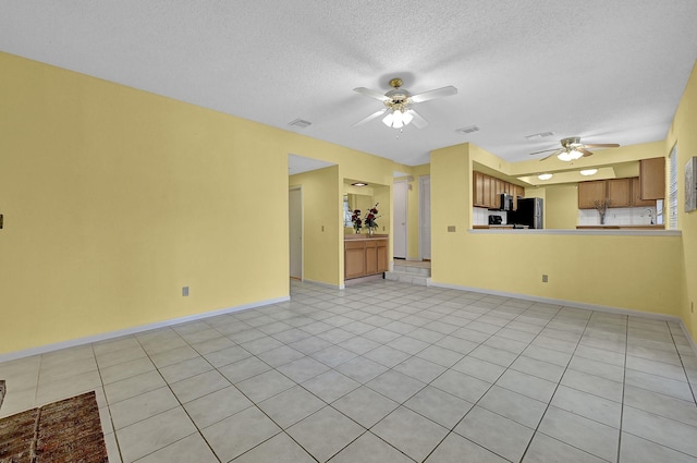 unfurnished living room featuring ceiling fan, a textured ceiling, and light tile patterned floors