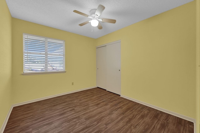 unfurnished bedroom featuring ceiling fan, a closet, dark hardwood / wood-style flooring, and a textured ceiling