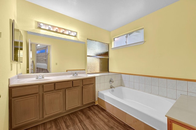 bathroom featuring wood-type flooring, vanity, and a bath