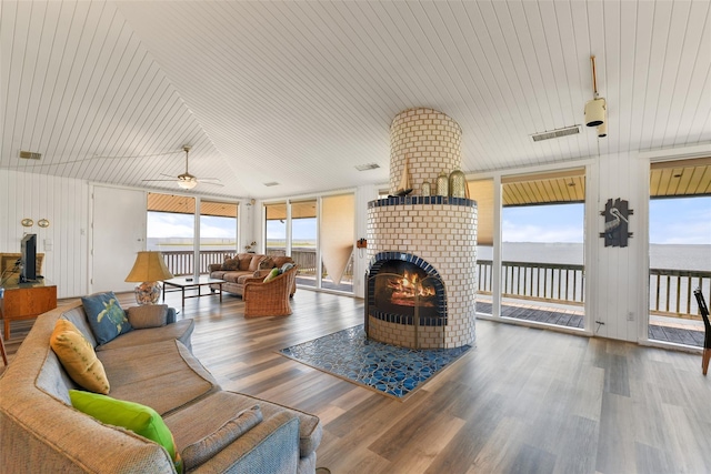 living room with hardwood / wood-style floors, a fireplace, plenty of natural light, a water view, and ceiling fan