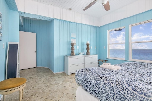 tiled bedroom featuring ceiling fan and a water view