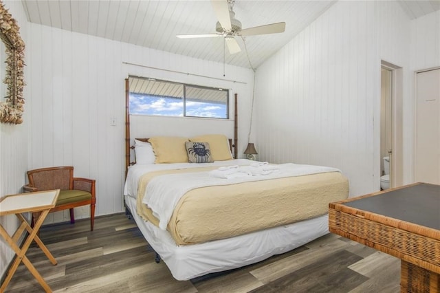 bedroom featuring ceiling fan, vaulted ceiling, dark wood-type flooring, and wooden walls