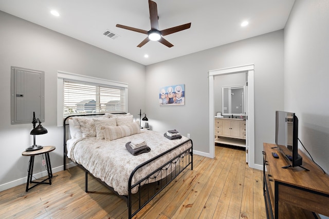 bedroom with ceiling fan, light wood-type flooring, ensuite bathroom, and electric panel