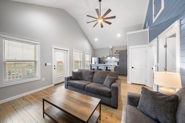 living room with high vaulted ceiling, ceiling fan, and light wood-type flooring