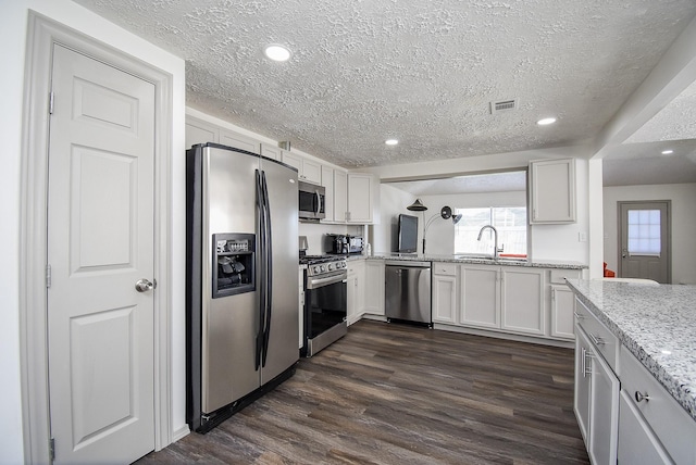 kitchen featuring a textured ceiling, stainless steel appliances, and white cabinets