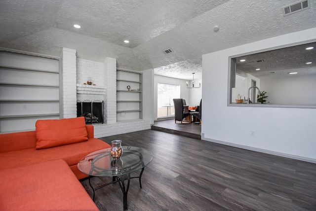 living room with a textured ceiling, a brick fireplace, dark hardwood / wood-style floors, and built in shelves