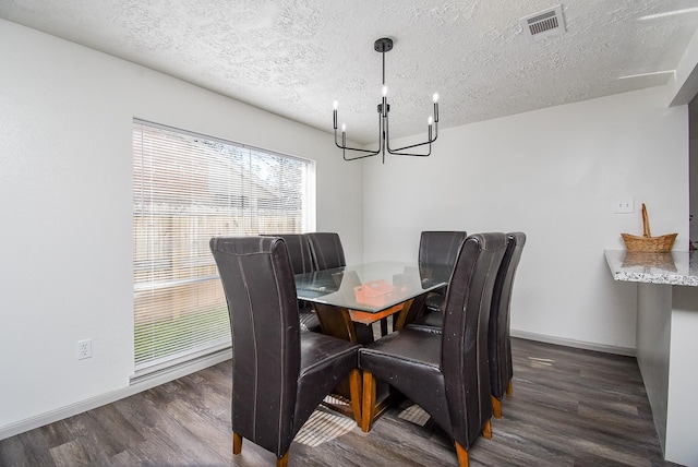 dining room with dark wood-type flooring, an inviting chandelier, and a textured ceiling