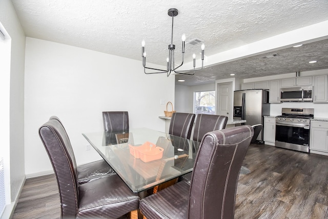 dining room featuring a textured ceiling, dark hardwood / wood-style flooring, and a chandelier