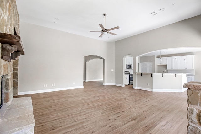 living room with ceiling fan, light wood-type flooring, and a fireplace