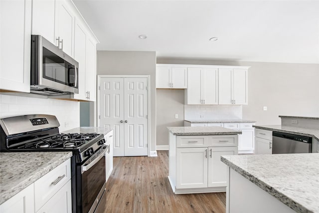 kitchen featuring stainless steel appliances, light hardwood / wood-style flooring, white cabinetry, and light stone countertops