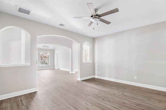 spare room with ceiling fan with notable chandelier and hardwood / wood-style floors