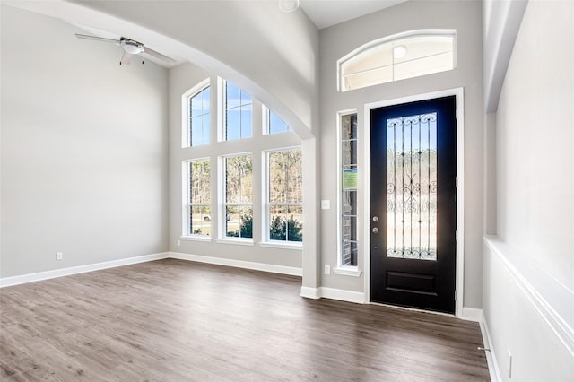 entrance foyer with ceiling fan, dark hardwood / wood-style floors, and a towering ceiling