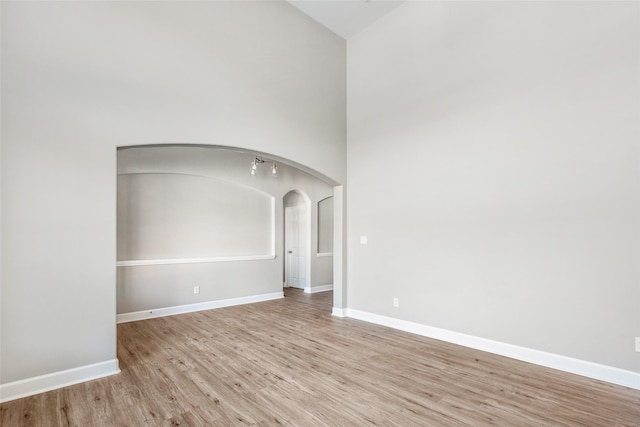 unfurnished room with light wood-type flooring and a high ceiling