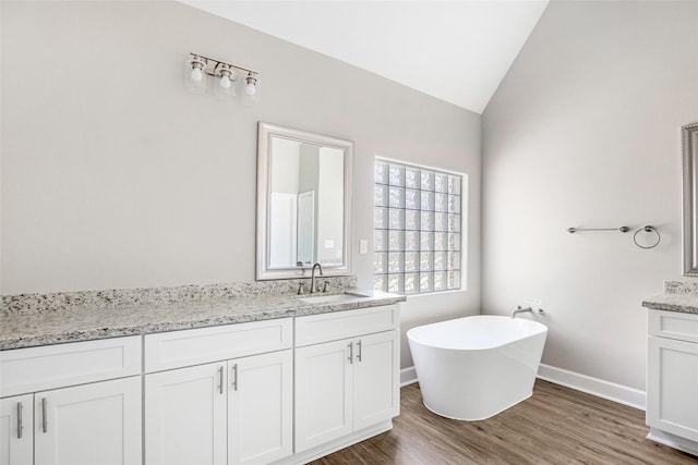 bathroom featuring lofted ceiling, vanity, a tub, and hardwood / wood-style floors