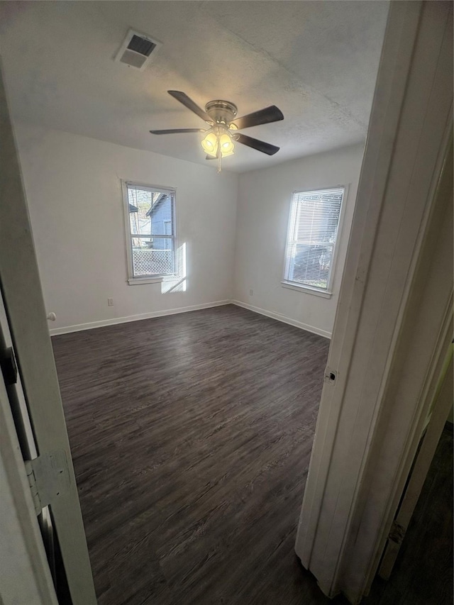 spare room with a textured ceiling, ceiling fan, and dark hardwood / wood-style flooring