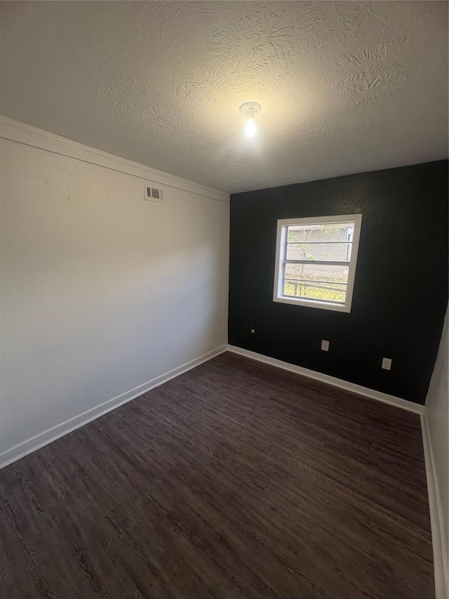 unfurnished room with dark hardwood / wood-style flooring and a textured ceiling