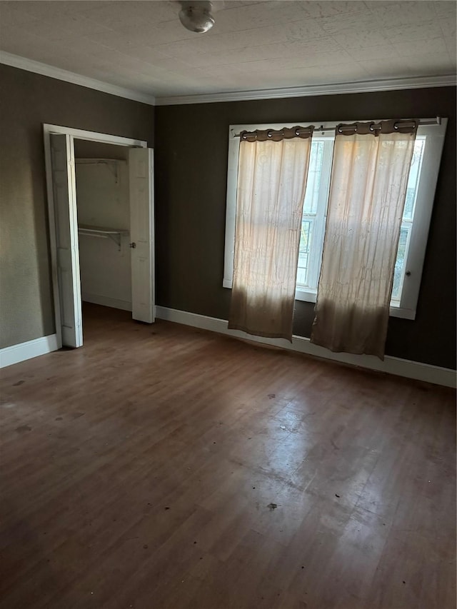 unfurnished bedroom with wood-type flooring, multiple windows, a closet, and ornamental molding