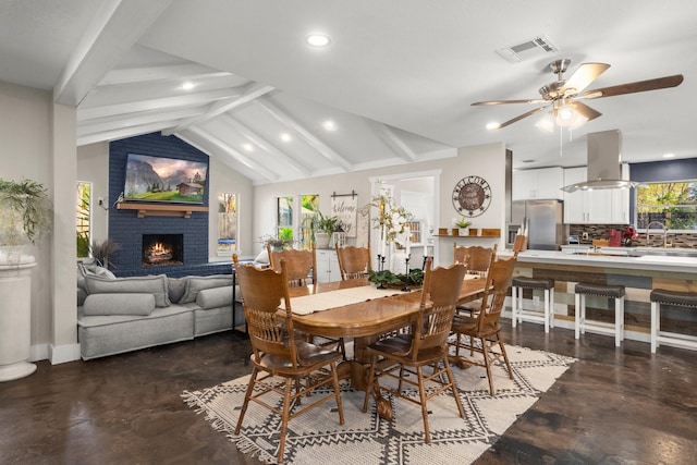 dining area with vaulted ceiling with beams, a fireplace, sink, and ceiling fan