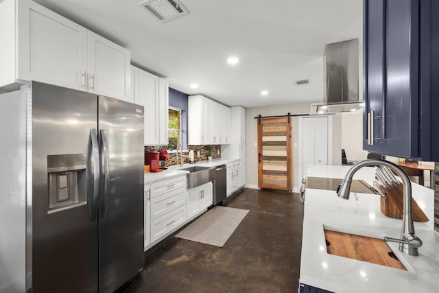 kitchen featuring appliances with stainless steel finishes, white cabinetry, sink, backsplash, and a barn door