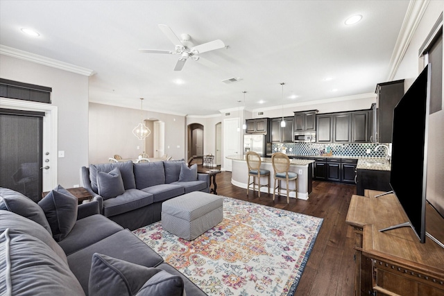 living room featuring ceiling fan, ornamental molding, and dark hardwood / wood-style floors