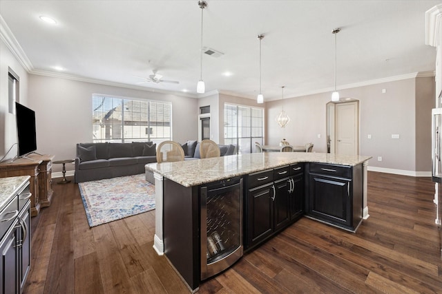 kitchen with hanging light fixtures, light stone countertops, beverage cooler, and a kitchen island