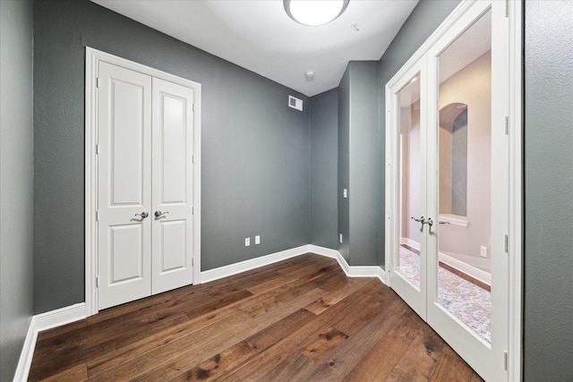 bedroom with a closet, dark hardwood / wood-style flooring, and french doors