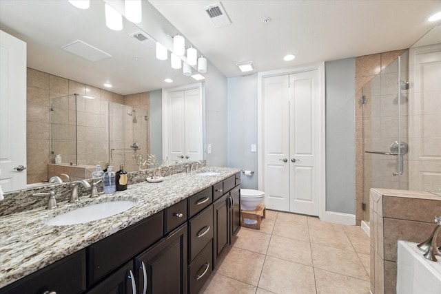 bathroom with a shower with door, vanity, tile patterned flooring, and toilet