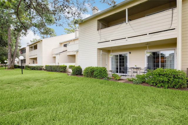 back of house with a lawn and a patio