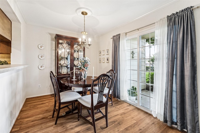 dining room with wood-type flooring, crown molding, and a notable chandelier