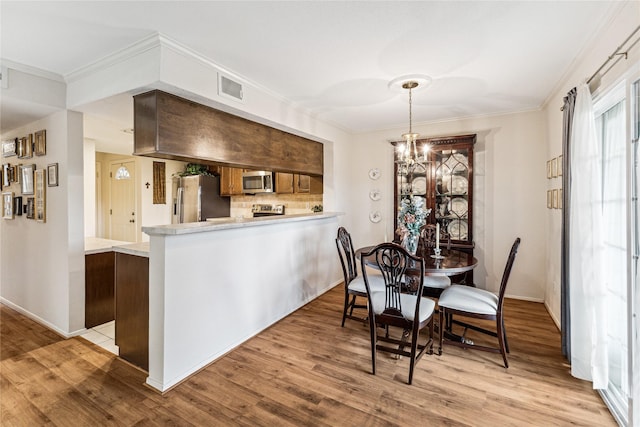 dining room with light hardwood / wood-style floors, crown molding, and a chandelier