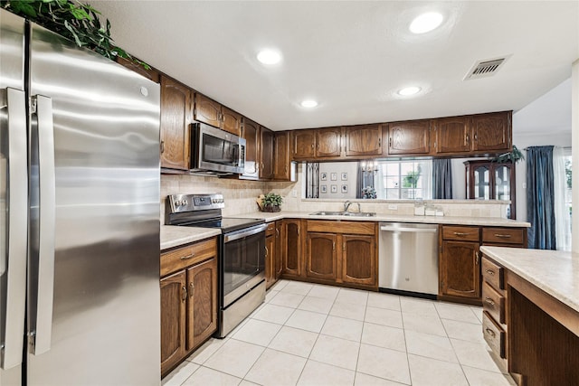 kitchen featuring appliances with stainless steel finishes, decorative backsplash, sink, kitchen peninsula, and light tile patterned flooring