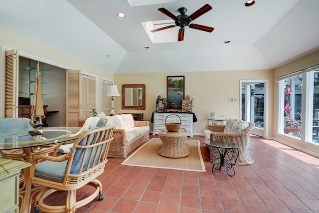 tiled living room featuring ceiling fan and lofted ceiling with skylight