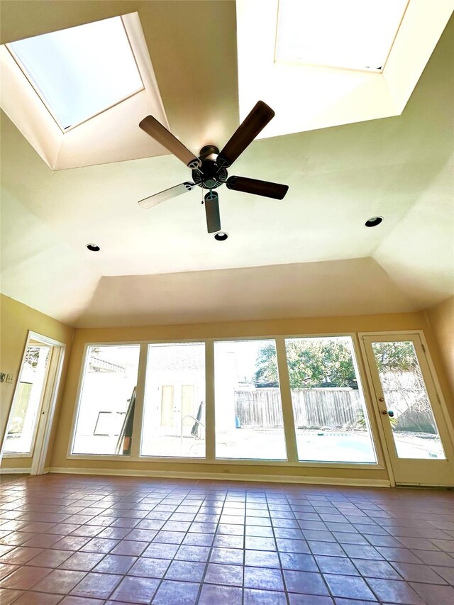 interior space with ceiling fan, a skylight, and a raised ceiling