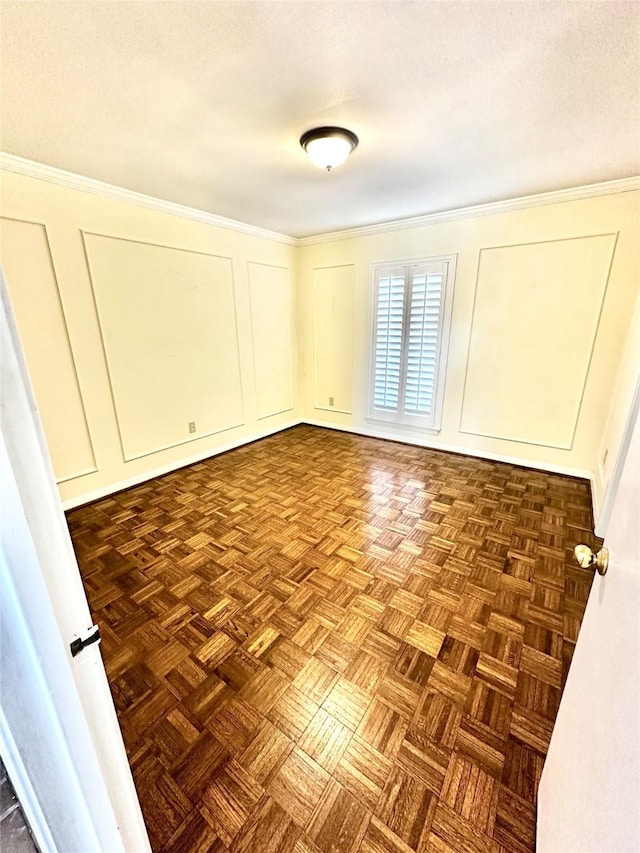 spare room featuring ornamental molding and dark parquet floors