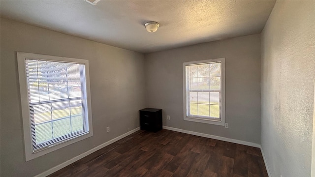 spare room with a textured ceiling and dark hardwood / wood-style flooring