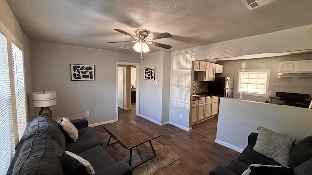 living room with a textured ceiling, ceiling fan, dark hardwood / wood-style floors, and sink