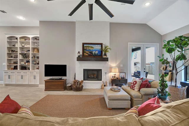 living room with ceiling fan, lofted ceiling, a fireplace, light hardwood / wood-style flooring, and french doors