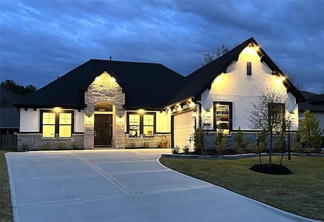 french country inspired facade featuring a garage and a front yard