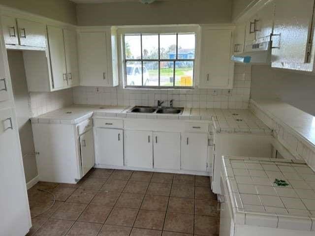 kitchen with sink, white cabinets, tile countertops, and tasteful backsplash