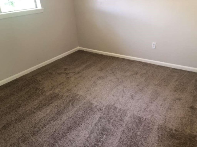 spare room with dark carpet