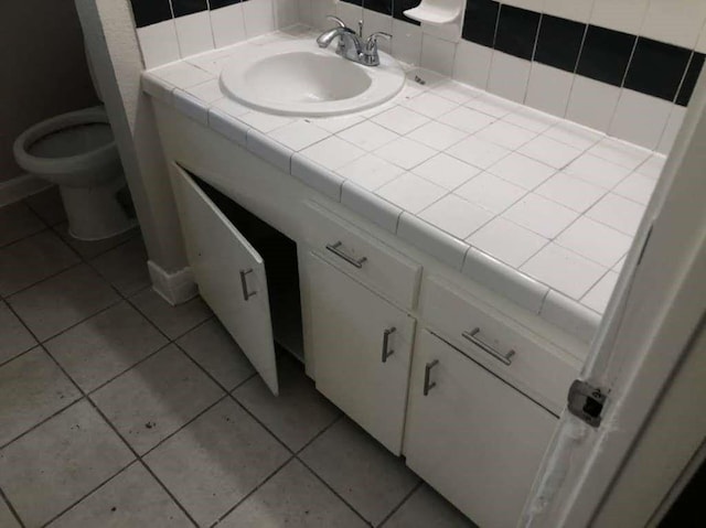 bathroom with toilet, vanity, and tile patterned floors