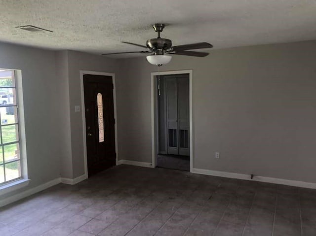 unfurnished room featuring ceiling fan, a textured ceiling, and a healthy amount of sunlight