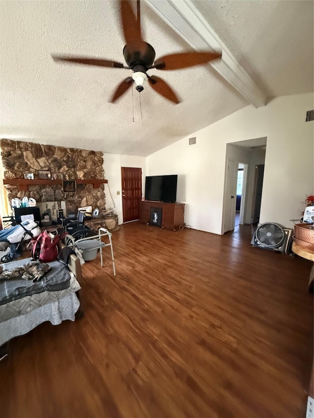 living room with ceiling fan, vaulted ceiling with beams, dark hardwood / wood-style flooring, and a textured ceiling